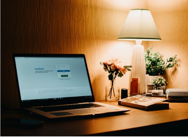 An open laptop on a nightstand with a lamp