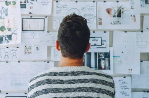 A man looking at creative and charts on a board