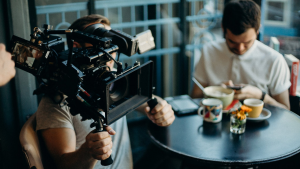 A camera man holding a professional camera shooting a scene